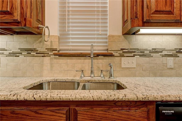 kitchen with sink, tasteful backsplash, and light stone countertops