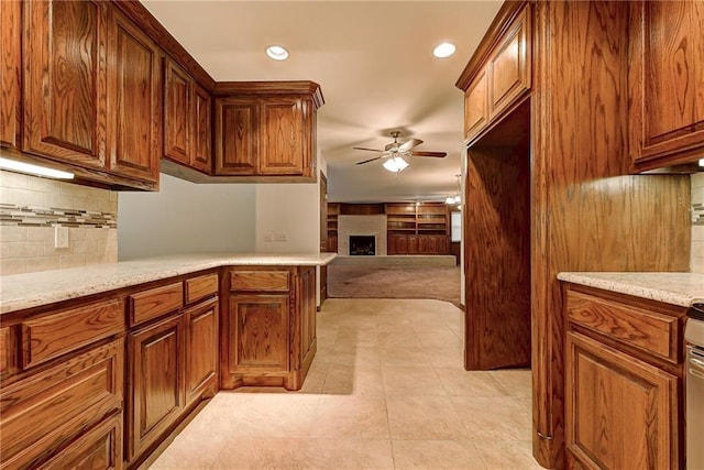 kitchen featuring kitchen peninsula, ceiling fan, tasteful backsplash, light stone counters, and light tile patterned flooring