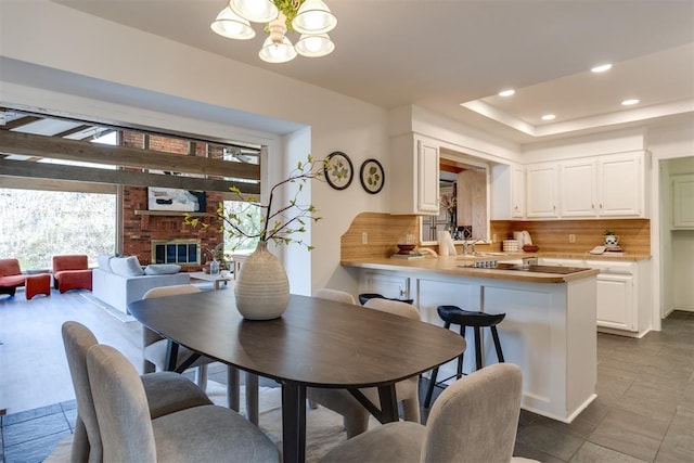 dining space with a brick fireplace and an inviting chandelier