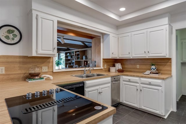 kitchen with sink, white cabinetry, black dishwasher, dark tile patterned flooring, and backsplash