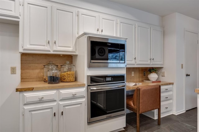 kitchen featuring built in microwave, white cabinetry, tasteful backsplash, and stainless steel oven