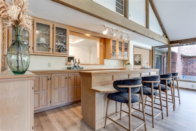 bar featuring vaulted ceiling with beams, light brown cabinets, and light hardwood / wood-style flooring