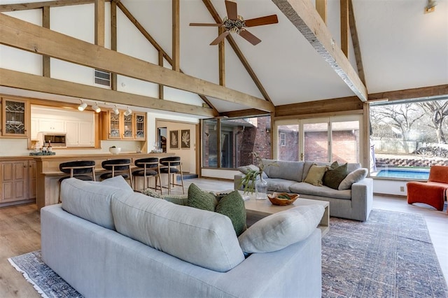 living room featuring ceiling fan, lofted ceiling with beams, and light wood-type flooring