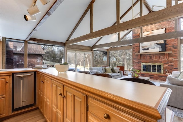 kitchen with beamed ceiling, kitchen peninsula, a fireplace, and light hardwood / wood-style floors