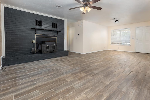 unfurnished living room with ceiling fan, a wood stove, and hardwood / wood-style floors