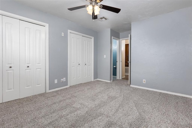 unfurnished bedroom with carpet floors, two closets, and ceiling fan