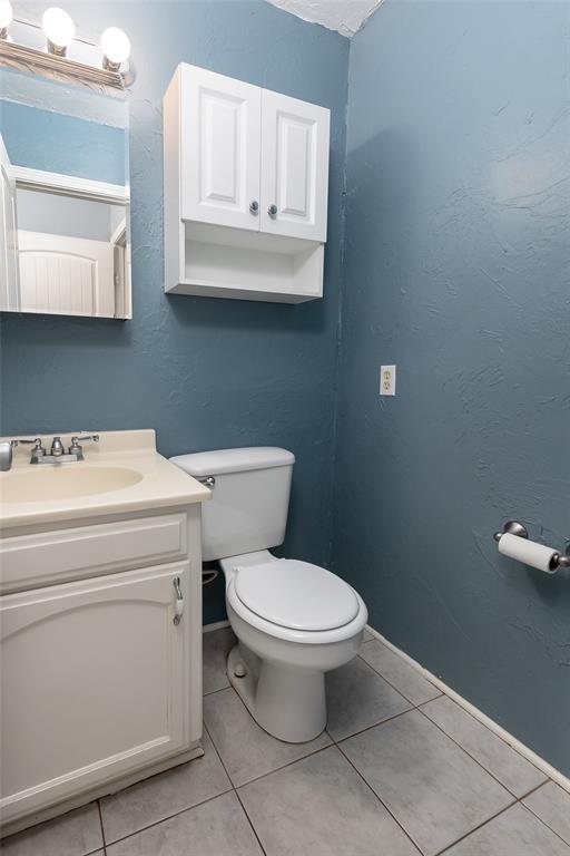 bathroom with toilet, tile patterned floors, and vanity