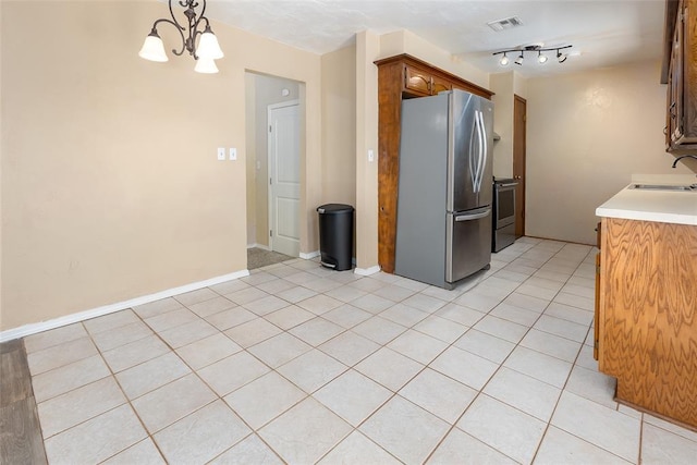 kitchen featuring pendant lighting, stainless steel appliances, sink, a chandelier, and light tile patterned flooring