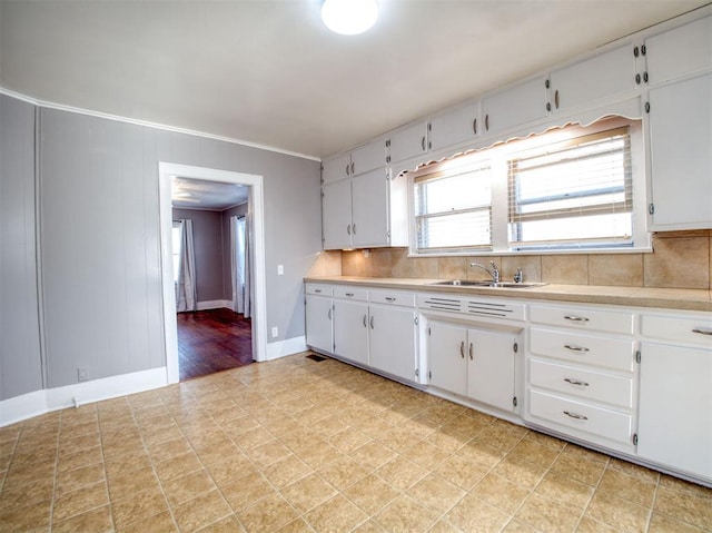 kitchen featuring sink, backsplash, white cabinets, and ornamental molding