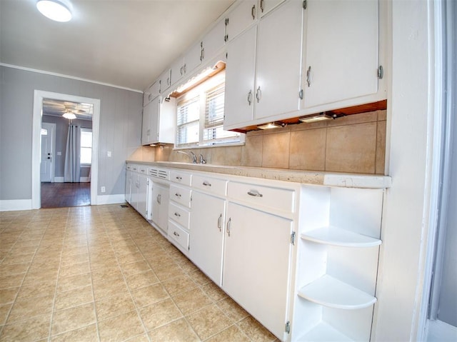 kitchen featuring white cabinets, sink, ceiling fan, light tile patterned floors, and crown molding