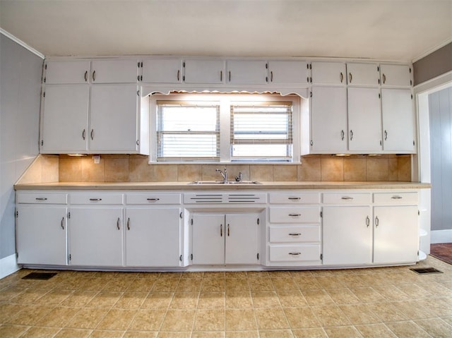 kitchen with sink, backsplash, and white cabinetry