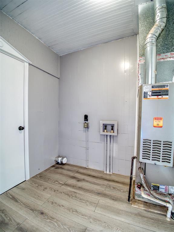 clothes washing area with wood-type flooring, washer hookup, and heating unit