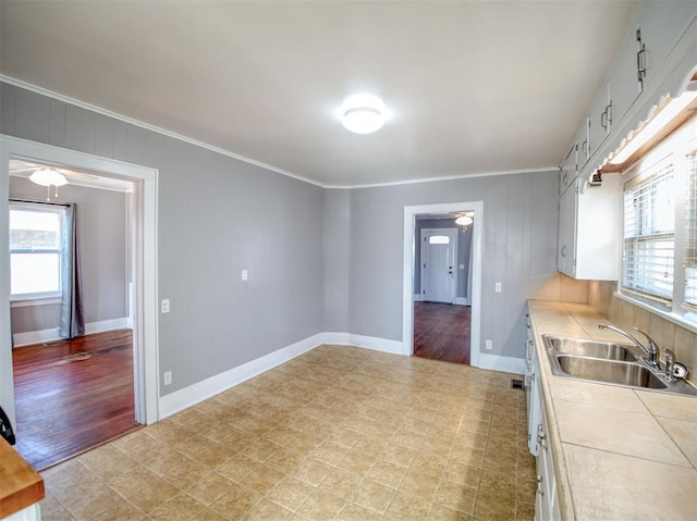 kitchen featuring sink, white cabinetry, crown molding, and plenty of natural light