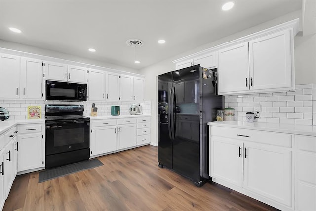 kitchen featuring white cabinets, dark hardwood / wood-style floors, decorative backsplash, and black appliances