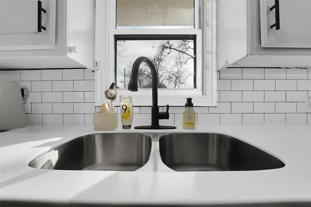 interior details with sink, backsplash, and white cabinets