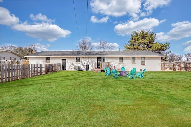 back of property with a yard and an outdoor fire pit