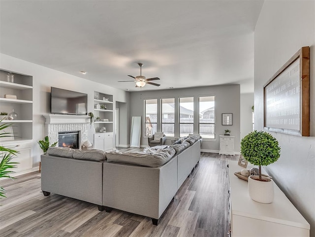 living room featuring hardwood / wood-style floors, ceiling fan, and built in shelves