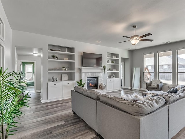 living room featuring hardwood / wood-style floors, built in features, and ceiling fan