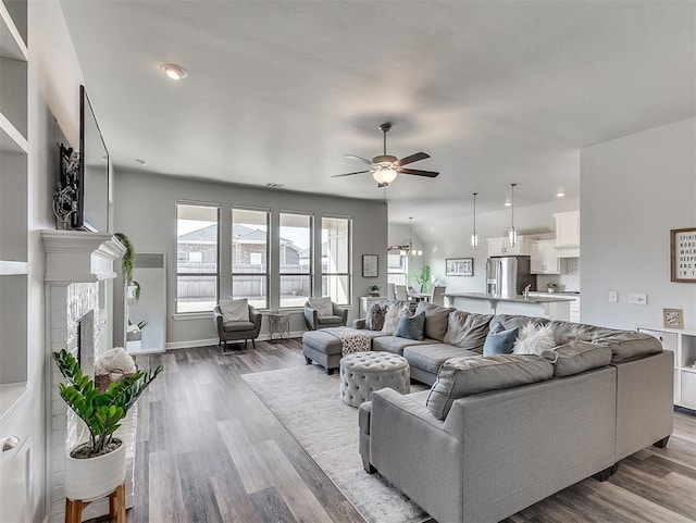 living room with a brick fireplace, ceiling fan, and light hardwood / wood-style flooring