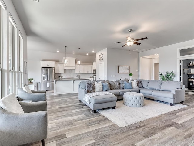 living room with ceiling fan, plenty of natural light, and light wood-type flooring