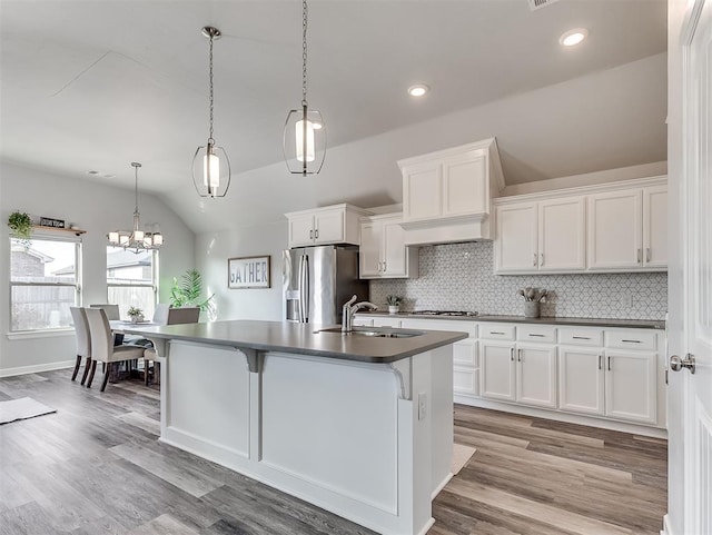 kitchen with a kitchen island with sink, sink, white cabinets, and stainless steel fridge with ice dispenser