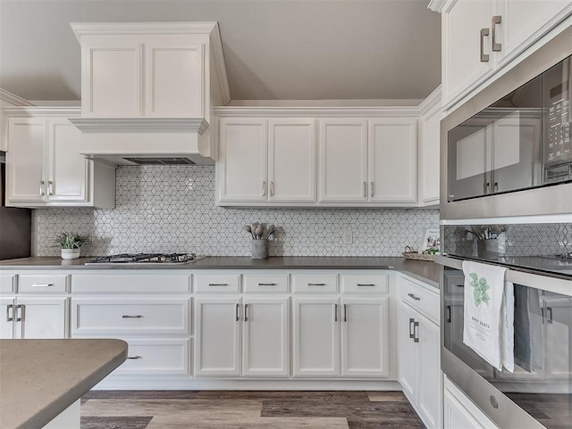 kitchen featuring white cabinetry, stainless steel appliances, light hardwood / wood-style floors, and backsplash