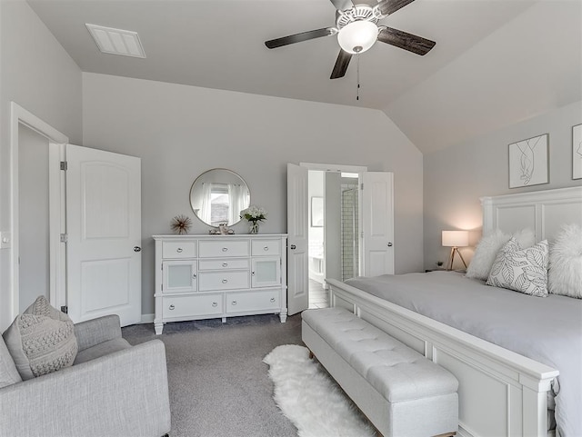 bedroom with vaulted ceiling, dark carpet, ensuite bathroom, and ceiling fan