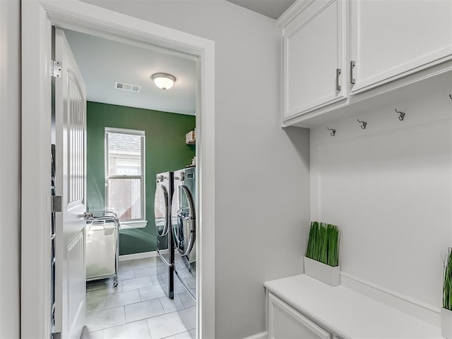 clothes washing area featuring cabinets, washer and dryer, and light tile patterned floors