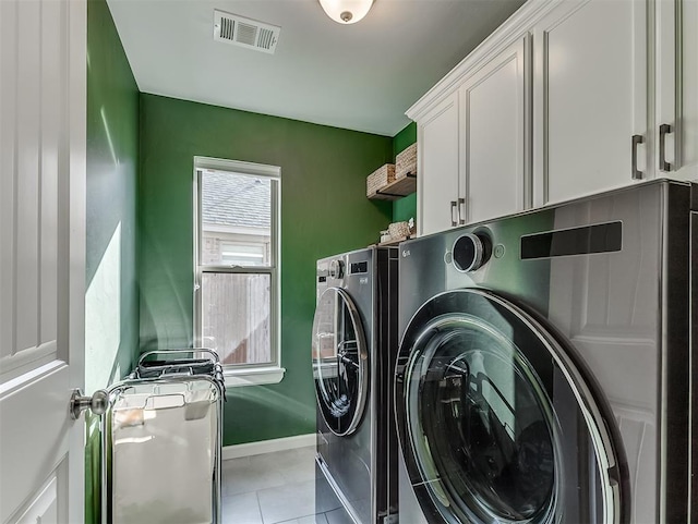 laundry area with light tile patterned floors, cabinets, and washing machine and clothes dryer