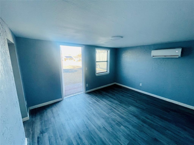 spare room featuring a textured ceiling, dark hardwood / wood-style flooring, and a wall mounted AC