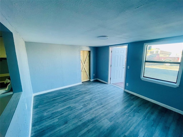 spare room featuring dark wood-type flooring and a textured ceiling