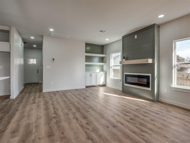 unfurnished living room featuring a large fireplace and light wood-type flooring