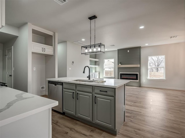 kitchen with gray cabinets, dishwasher, sink, hanging light fixtures, and a center island with sink