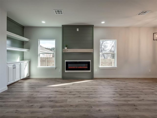 unfurnished living room featuring wood-type flooring and a large fireplace