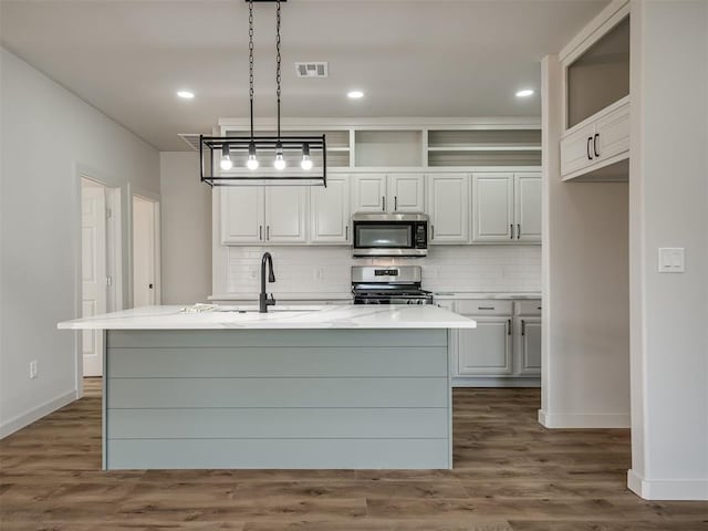 kitchen featuring pendant lighting, appliances with stainless steel finishes, sink, and a kitchen island with sink