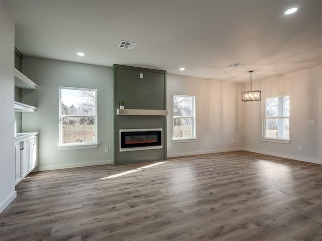 unfurnished living room featuring a healthy amount of sunlight, a large fireplace, and dark hardwood / wood-style flooring