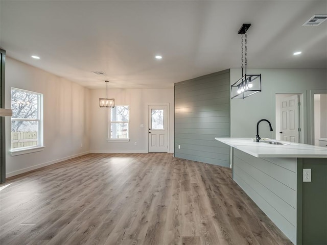 interior space featuring plenty of natural light, sink, pendant lighting, and a kitchen island with sink