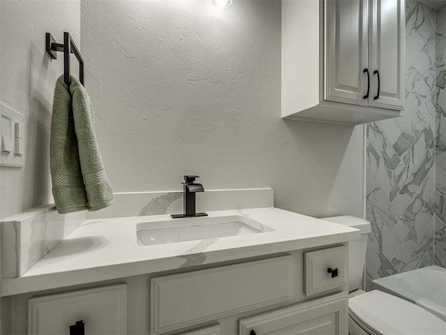 bathroom featuring toilet, a textured wall, and vanity