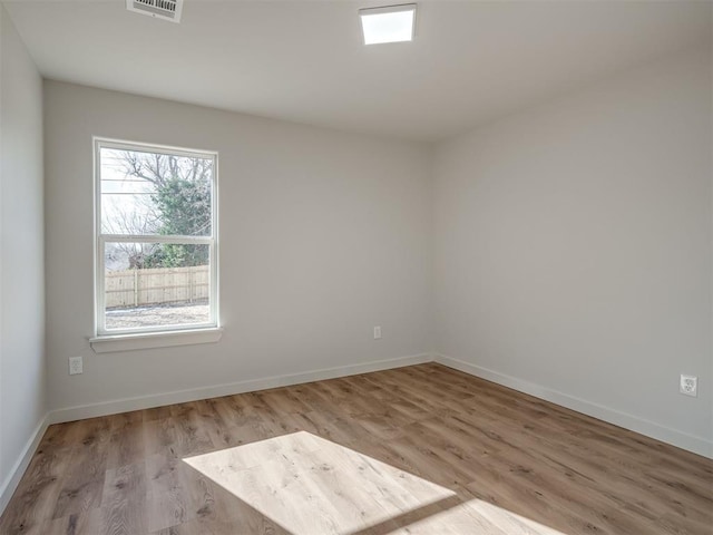 empty room with light wood-type flooring, visible vents, and baseboards