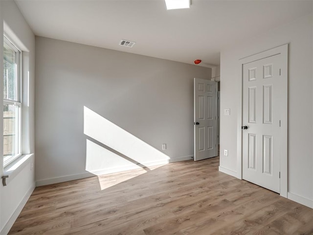 empty room featuring light wood-type flooring, visible vents, and baseboards