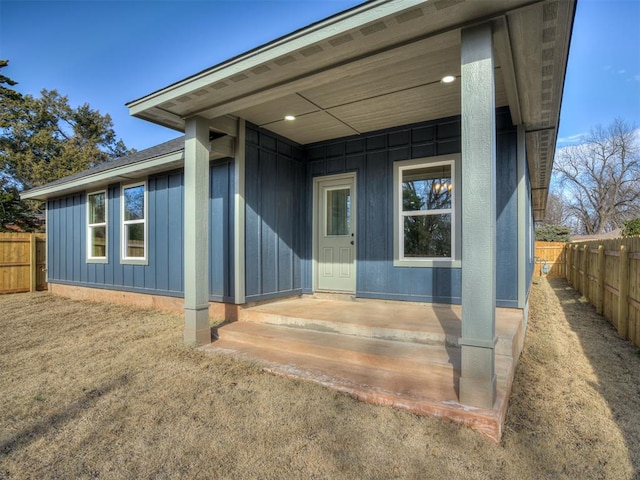 entrance to property featuring board and batten siding and fence