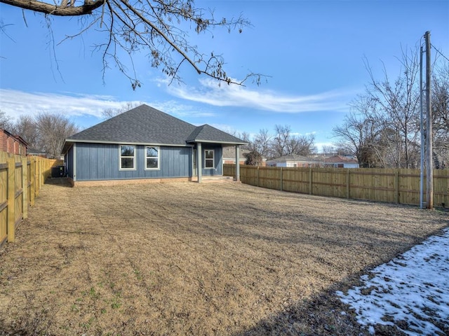 view of front of property featuring a shingled roof, a front yard, and a fenced backyard