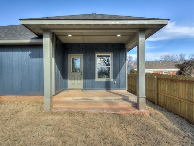 entrance to property with roof with shingles and fence