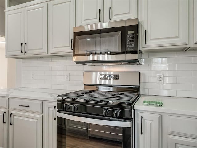 kitchen featuring tasteful backsplash, stainless steel microwave, black gas range, and white cabinets