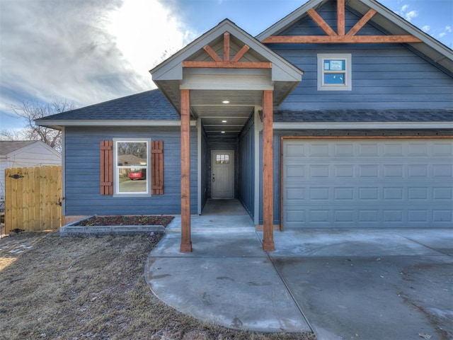 view of front of property with a garage, concrete driveway, roof with shingles, and fence