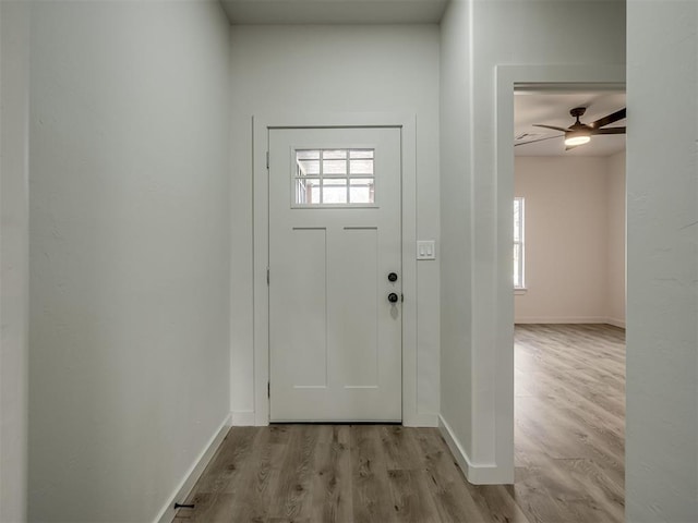 entryway featuring light wood finished floors, ceiling fan, and baseboards