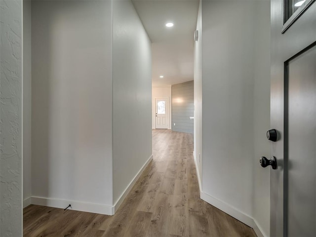 hallway featuring baseboards, recessed lighting, and light wood-style floors