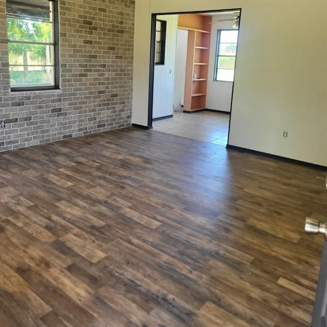 empty room featuring brick wall and dark hardwood / wood-style flooring