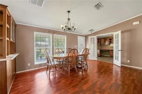 dining room with dark wood-type flooring, a chandelier, crown molding, and french doors