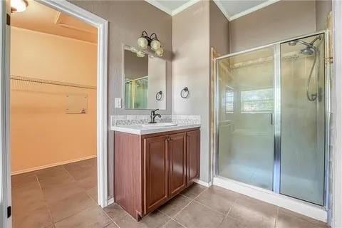 bathroom with tile patterned flooring, a shower with door, and vanity